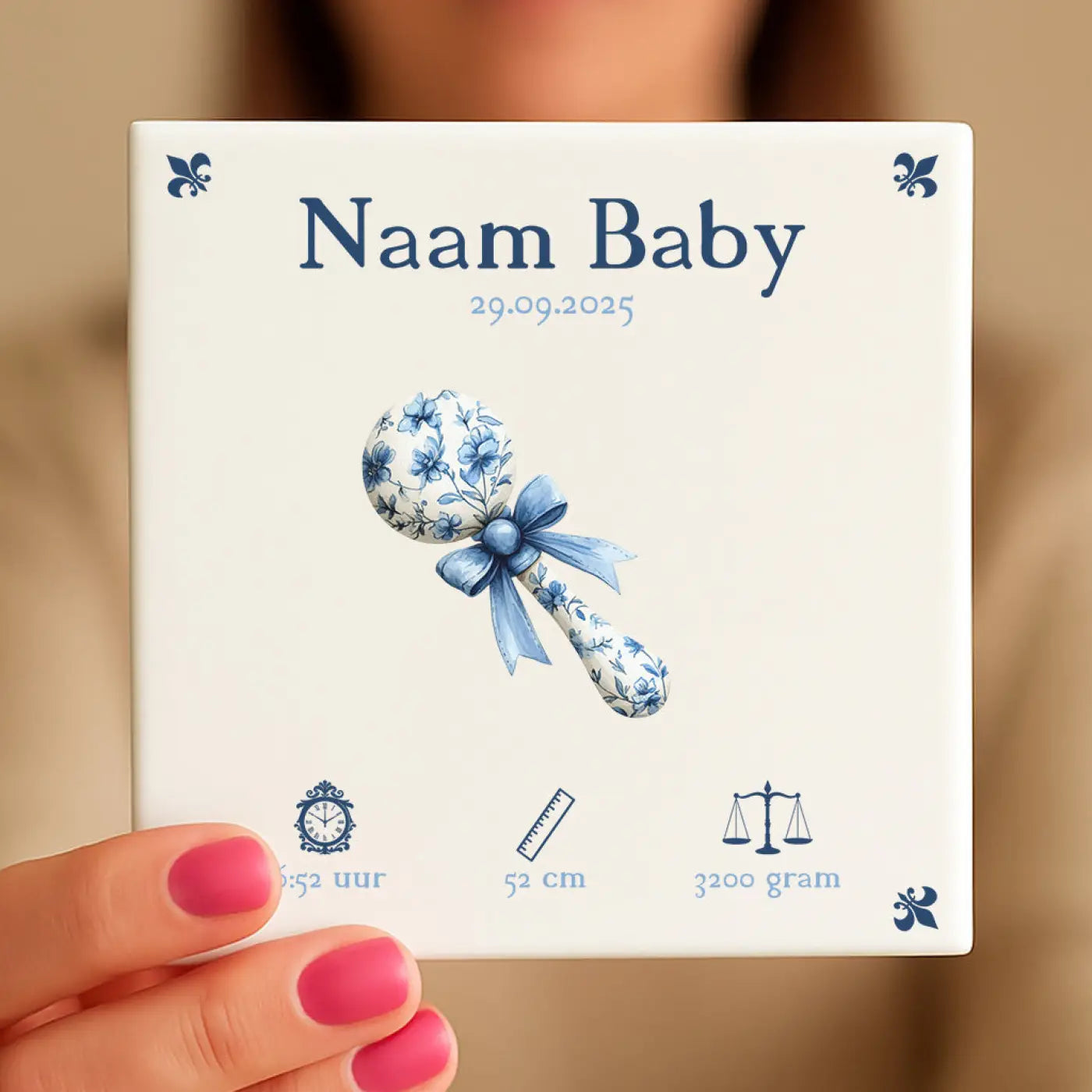 Witte keramische baby rammelaar met blauwe bloemmotieven en bijpassend lint uit baby tegeltje blauw rammelaar
