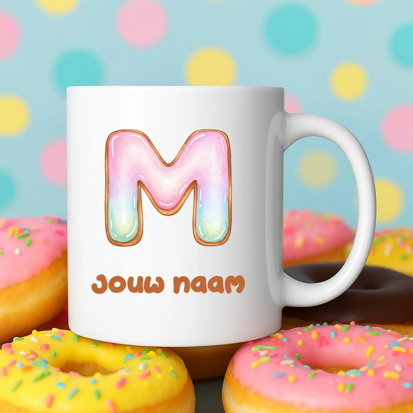 Witte keramische mok met een kleurrijke glimmende donutvormige letter m met roze en lichtblauwe glazuur en bruine koekjesrand